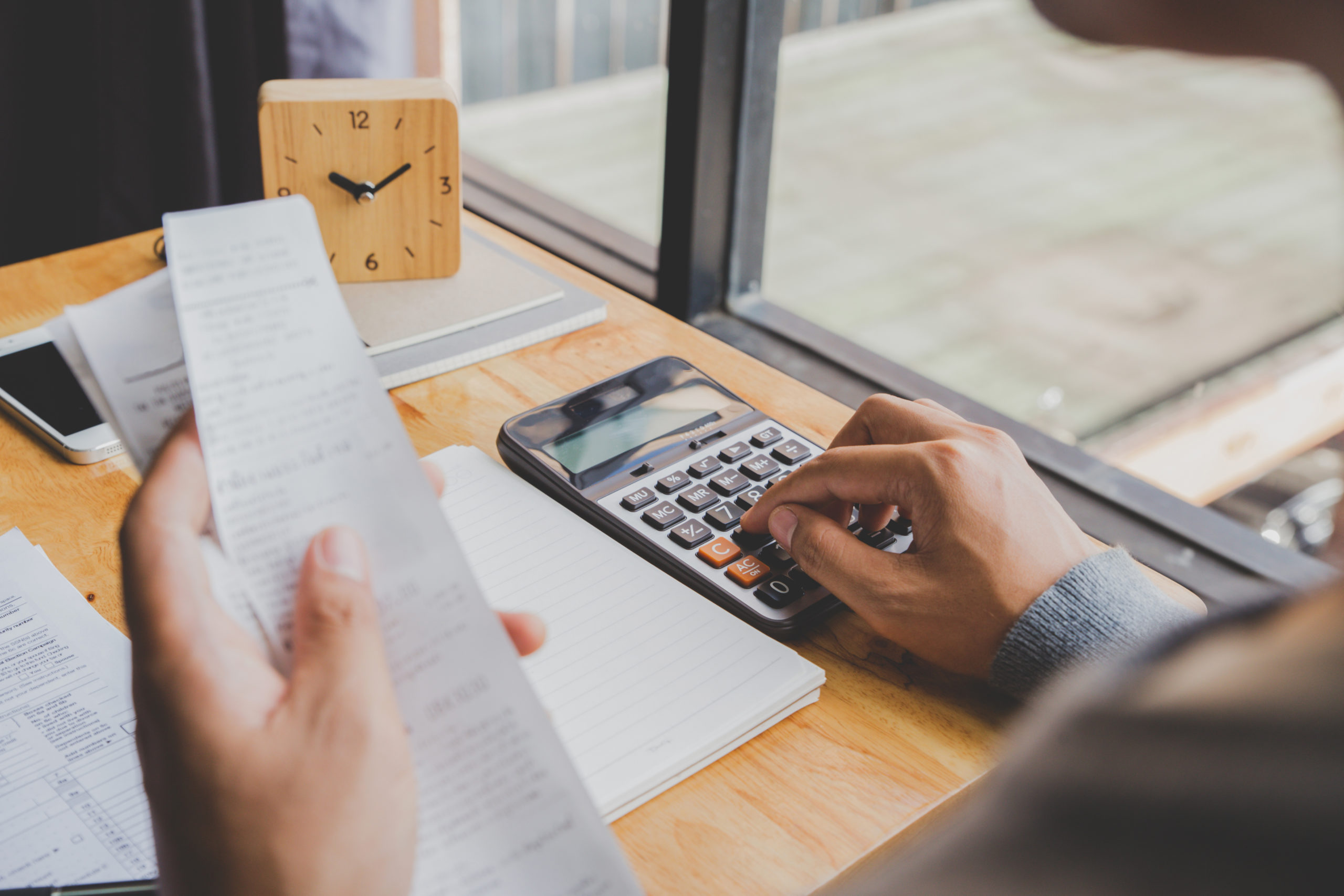 Young man using calculator and calculate bills in home office.